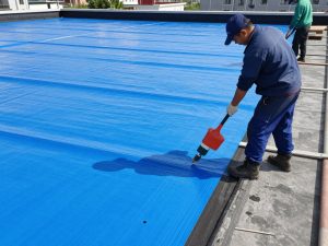 تطبيق مواد العزل المائي على سطح مبنى بواسطة مقاول عازل اسطح محترف