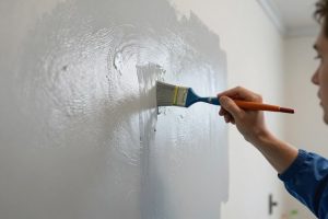 فني محترف يقوم بتطبيق صباغة لامعة على جدار